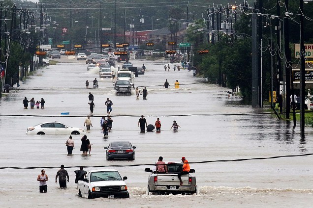 Pessoas caminham por uma rua inundada após a passagem do furacão Harvey em Houston, no Texas - 28/08/2017