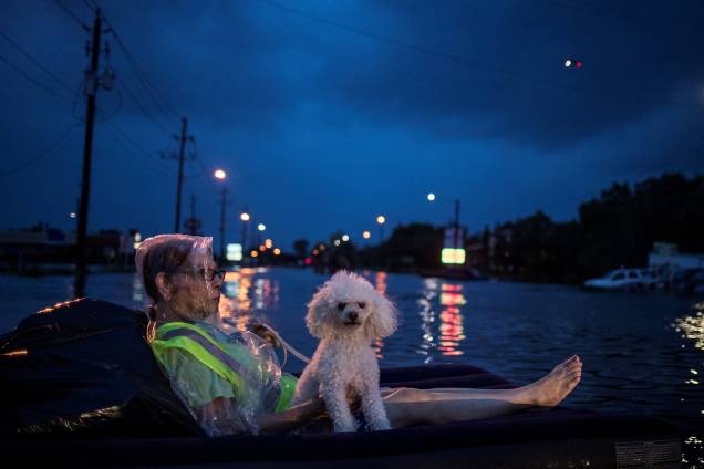 Mulher usa um colchão de ar para flutuar com seu cão acima das águas de inundação provocadas pelo furacão Harvey enquanto espera para ser resgatada em Houston, no estado americano do Texas - 27/08/2017