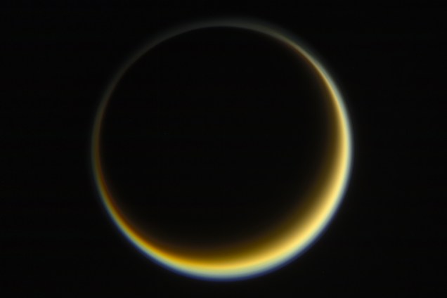 Cassini fotografa face escura de Titã, a maior lua de Saturno, enquanto o Sol ilumina o outro lado. É possível observar a névoa alaranjada que existe na atmosfera do astro.