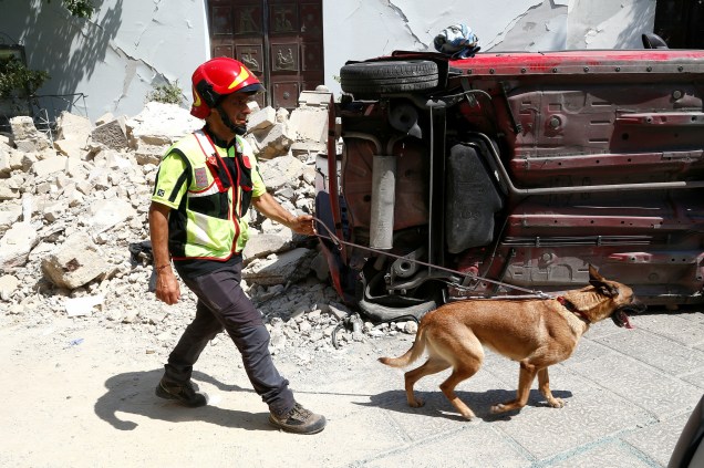 Membro da equipe de resgate inspeciona com a ajuda de um cachorro a área danificada após um terremoto na ilha de Ischia, ao largo da costa de Nápoles, na Itália - 22/08/2017