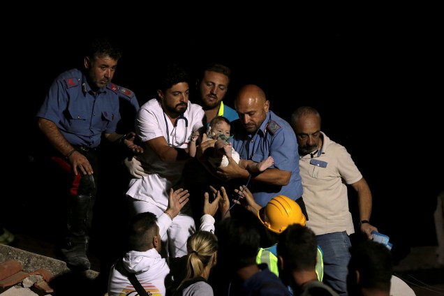 Oficial de polícia e um médico carregam uma criança após terremoto atingir a ilha de Ischia, na costa de Nápoles, na Itália - 22/08/2017