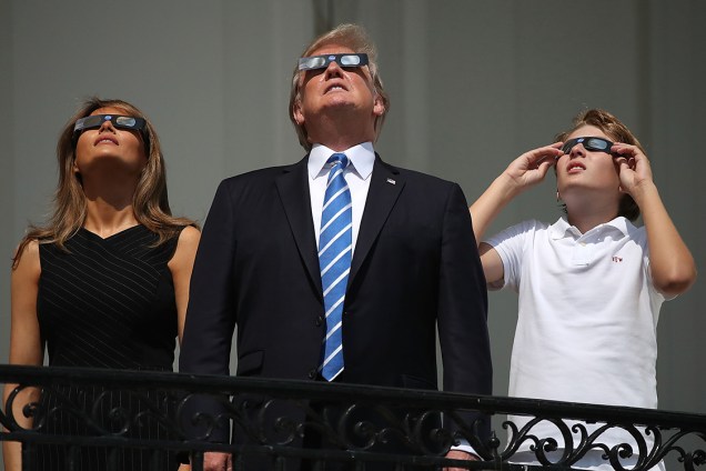 Presidente Donald Trump e sua esposa, Melania Trump, e o filho do casal, Barron Trump, observam o eclipse solar total no balcão da Casa Branca, em Washington