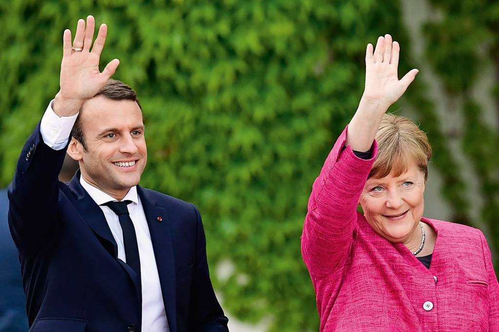 German Chancellor Angela Merkel and French President Emmanuel Macron wave to the crowds during a welcoming ceremony a day after the new French president took office on May 15, 2017 at the chancellery in Berlin. / AFP PHOTO / Tobias SCHWARZ