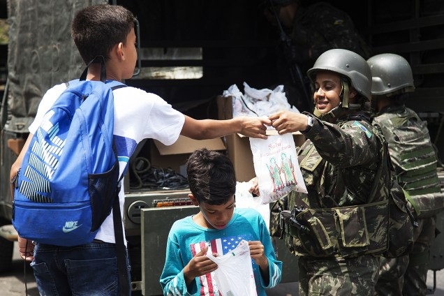 Mulheres do Exército distribuem doces e panfletos para crianças da favela da Rocinha, na zona sul do Rio de Janeiro, enquanto a operação de busca continua com revistas nas entradas da comunidade - 27/09/2017