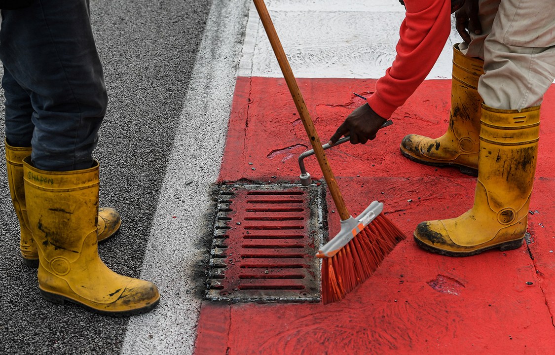 Trabalhadores consertam tampa de bueiro solta, após piloto francês Romain Grosjean sofrer pequeno acidente na pista, durante o Grand Prix de Formula 1, na Malásia