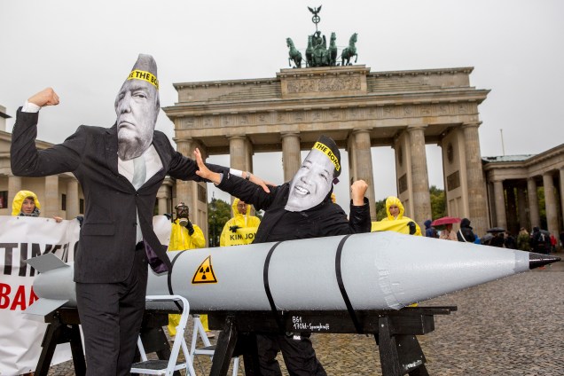 Manifestantes vestidos com máscaras do presidente norte-americano Donald Trump e do norte-coreano Kim Jong-Un, são fotografados ao lado de uma representação de bomba atômica durante um protesto pacifista organizado por idealistas anti-nucleares em Berlim, na Alemanha- 13/09/2017
