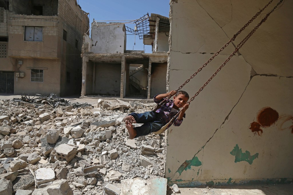Imagens do dia - Menino brinca em balanço na Síria