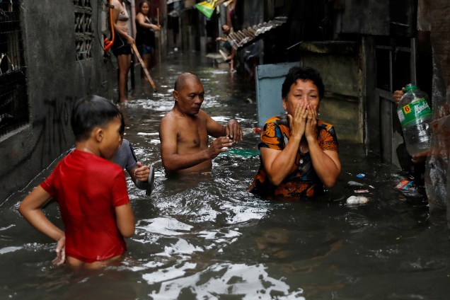 Moradores atravessam as enchentes em Quezon City, em Metro Manila, durante uma tempestade que provoca inundações na principal ilha de Luzon, nas Filipinas - 12/09/2017