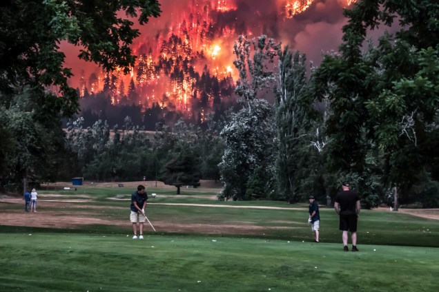 Foto tirada em 4 de setembro mostra pessoas jogando golfe durante um incêndio incêndio florestal  em North Bonneville, Washington, Estados Unidos - 04/09/2017