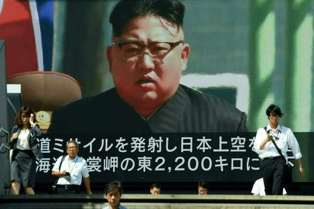 Pedestres caminham em frente a um telão no centro de Tóquio durante transmissão de um telejornal com a imagem do ditador norte-coreano Kim Jong-Un, após a realização de mais um teste de mísseis que passou sobre o território japonês - 15/09/2017