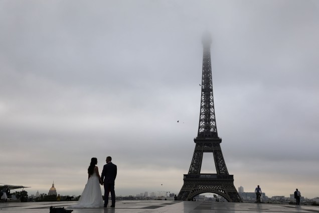 Jovem casal posa para sessão de fotos na PRaça do Trocadero em frente à Torre Eiffel cercada por nuvens, em Paris - 05/09/2017