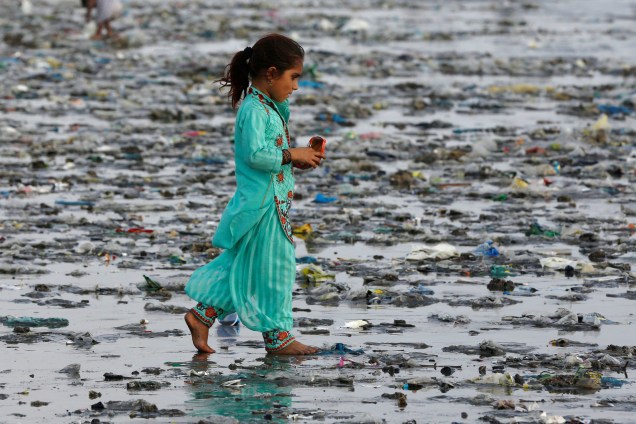 Uma menina caminha sobre o lixo deixado pelas ondas do mar na praia de Clifton, em Karachi, no Paquistão - 05/09/2017