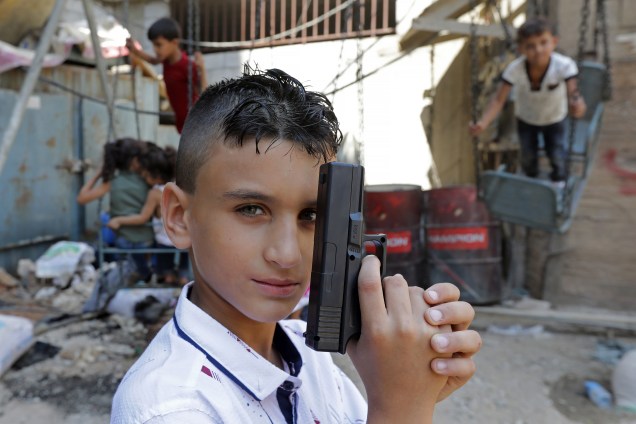 Um jovem refugiado sírio posa para uma foto em uma rua no campo de refugiados palestinos de Shatila, nos subúrbios do sul da capital libanesa Beirute, enquanto brinca com outras crianças - 01/09/2017