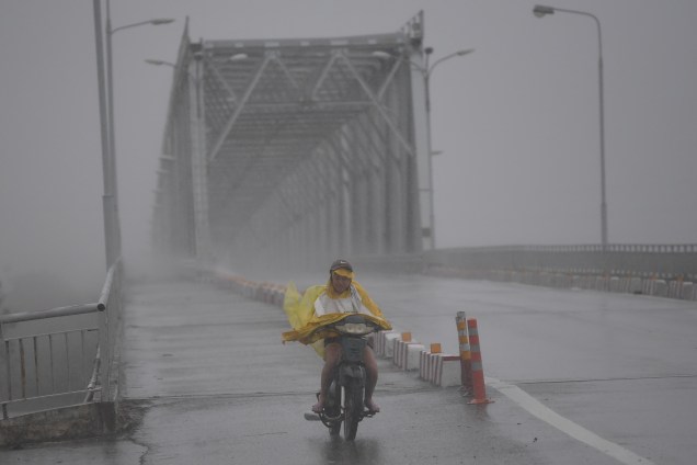 Mulher em uma moto atravessa uma ponte durante tempestade provocada pelo tufão Doksuri na província central de Ha Tinh, na costa central do Vietnã - 15/09/2017
