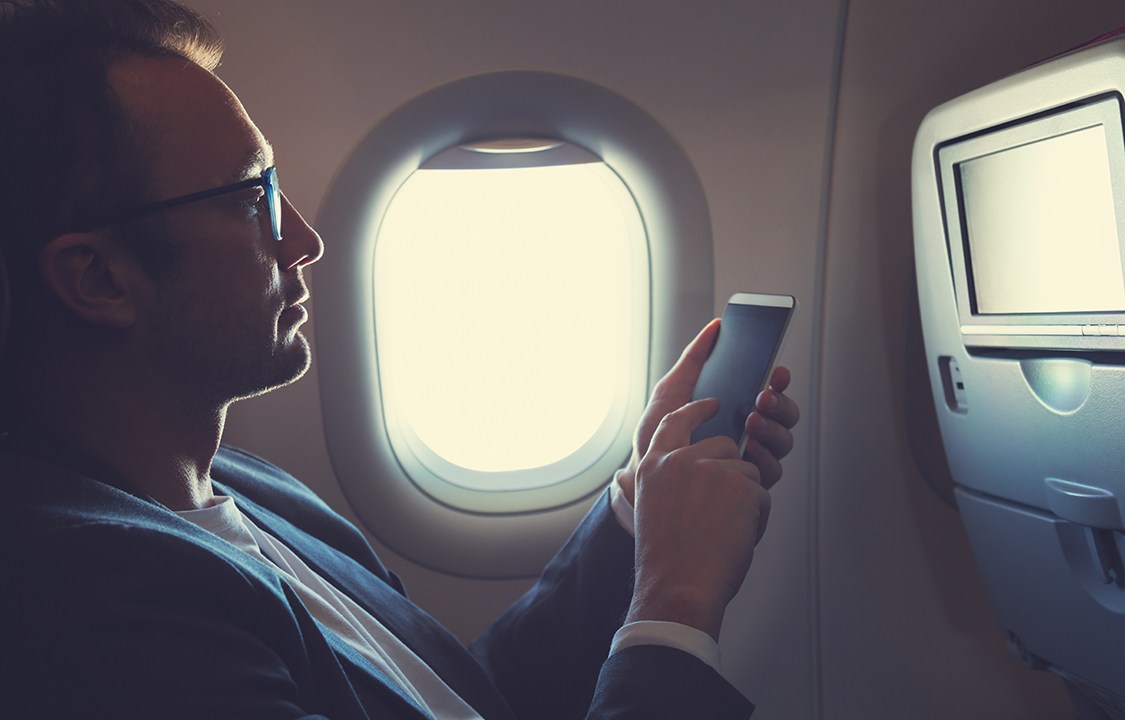 Homem usando smartphone em avião