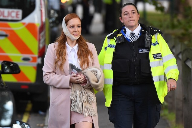 Policial acompanha uma mulher ferida após uma bomba caseira explodir dentro do vagão de um trem na Estação Parsons Green, da District Line, conhecida como “linha verde” em Londres. A polícia trata o caso como terrorismo - 15/09/2017