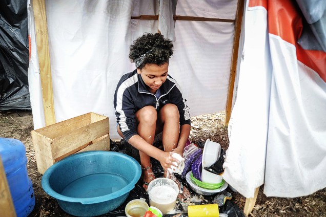 Menina lava louça em ocupação do Movimento dos Trabalhadores Sem Teto (MTST) em um terreno em São Bernardo do Campo