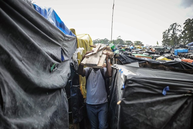 Militante carrega estacas de madeira para construir uma barraca, em ocupação do MTST em um terreno em São Bernardo do Campo
