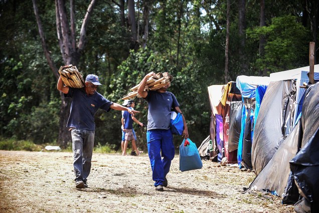 Militantes carregam estacas de madeira para construir barracas, em ocupação do MTST em um terreno em São Bernardo do Campo