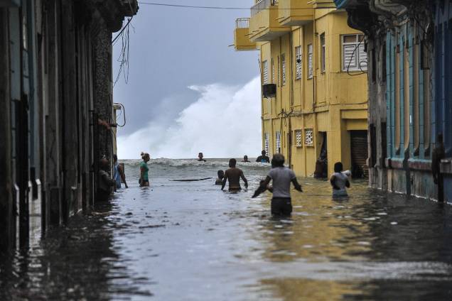 Moradores atravessam uma rua inundada perto do Malecón em Havana após passagem do furacão Irma em Cuba - 10/09/2017