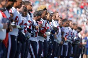 Jogadores do Houston Texas ficam de braços dados durante hino nacional que antecede a partida em forma de protesto contra Donald Trump, que defendeu a demissão de jogadores que protestassem em campo