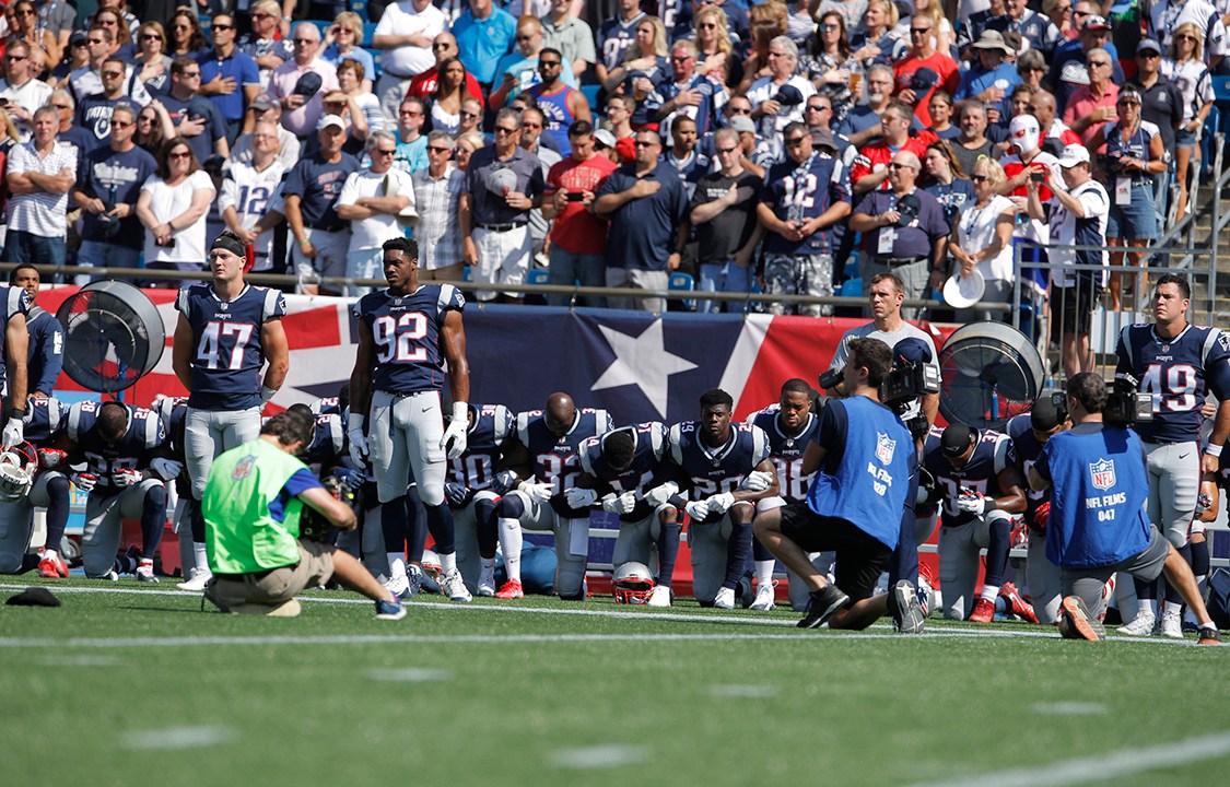 Jogadores do New England Patriots ficam de braços dados durante hino nacional que antecede a partida em forma de protesto contra Donald Trump, que defendeu a demissão de jogadores que protestassem em campo