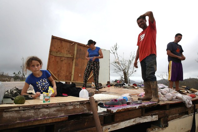 Família desabrigada junta restos de pertences após ter casa destruída pelo furacão Maria, em Hayales de Coamo, Porto Rico