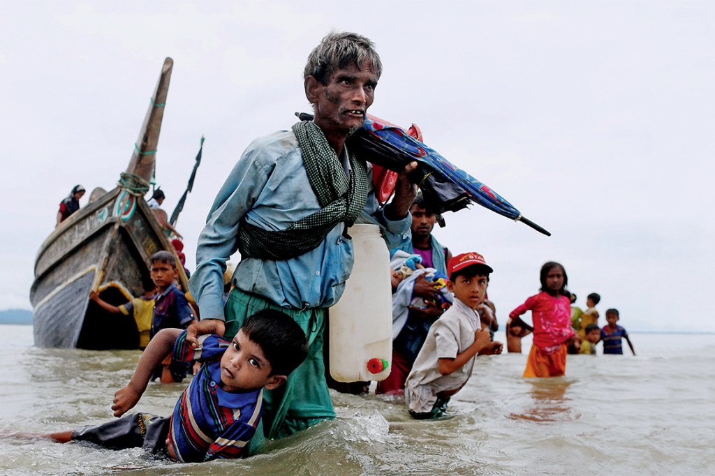 REFILE - QUALITY REPEAT A Rohingya refugee man pulls a child as they walk to the shore after crossing the Bangladesh-Myanmar border by boat through the Bay of Bengal in Shah Porir Dwip, Bangladesh, September 10, 2017. REUTERS/Danish Siddiqui TPX IMAGES OF THE DAY