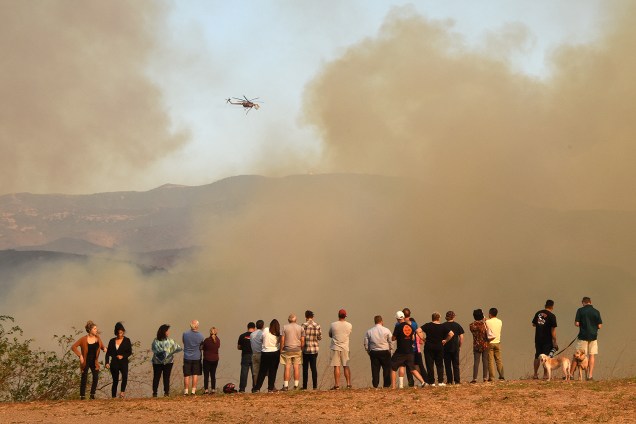 Um helicóptero derrama água como uma tentativa de apagar as chamas, em Orange, na Califórnia