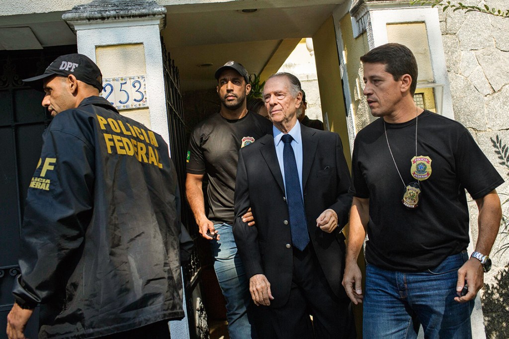 Brazil's Olympic Committee chief Carlos Nuzman (C) is escorted from his home by federal police in Rio de Janeiro on October 5, 2017. Brazilian police on October 5 arrested the chairman of the Brazilian Olympic Committee as part of a probe into alleged buying of votes to secure Rio's hosting of the 2016 Games. / AFP PHOTO / Mauro PIMENTEL