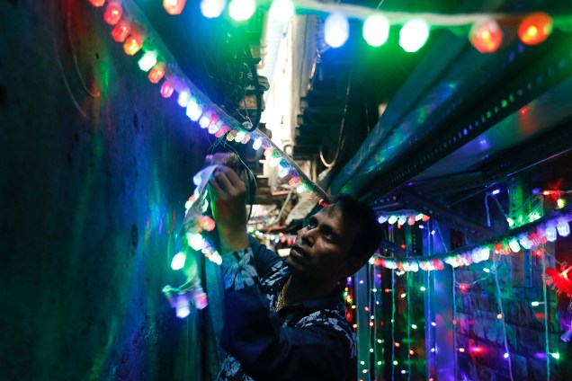 Um homem se prepara para o festival hindu Diwali pendurando luzes em um beco, em uma favela de Mumbai, na Índia - 28/10/2017