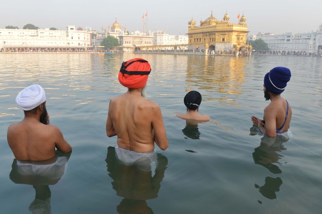 Devotos Sikhis indianos mergulham no tanque de águas sagradas do Templo Dourado pela manhã para rezar, durante o Festival Hindu Diwali, na cidade de Amritsar - 19/10/2017