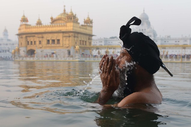 Um devoto Sikh toma um banho matinal no tanque de água sagrada 'sarovar' durante o Festival Diwali, no Templo Dourado, em Amritsar, na Índia - 19/10/2017