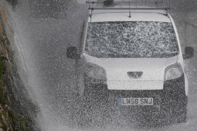 Um carro é visto na via beira-mar enquanto grandes ondas se chocam com as barragens do mar e o porto de Porthleven, na Cornualha, na chegada da tempestade Ophelia no Reino Unido - 16/10/2017