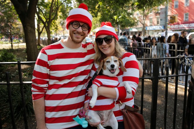 Casal vestido como o personagem de "Onde está o Wally" segura seu cachorro durante o desfile anual de cães de Halloween no Tompkins Square Park em Nova York