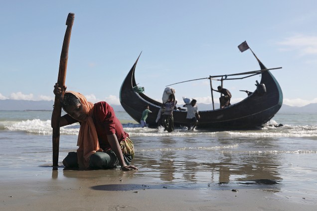 Uma mulher descansa após chegar em um pequeno barco de madeira na costa de Teknaf, em Bangladesh, vindos de Myanmar -  02/10/2017