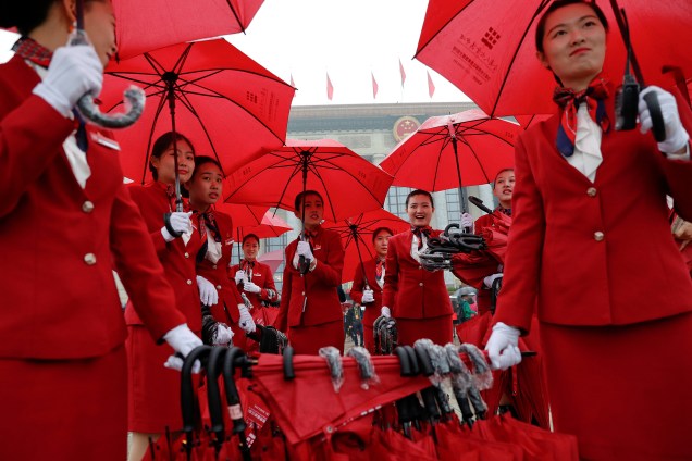 Mulheres se encarregam de cuidar dos guarda-chuvas usados pelos delegados que chegam para a sessão de abertura do 19º Congresso Nacional do Partido Comunista da China, no Grande Salão do Povo em Pequim, na China - 18/10/2017