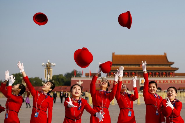 Mulheres jogam seus chapéus para cima enquanto posam para fotógrafos na Praça Tiananmen antes do início da sessão de encerramento do 19º Congresso Nacional do Partido Comunista da China, em Pequim - 24/10/2017