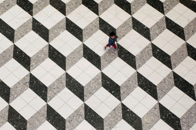 Um garoto é fotografado andando sobre um piso de construção geométrica dentro de um shopping center, em Tóquio, no Japão