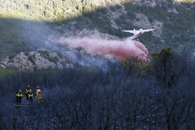 Bombeiros franceses observam um avião que tenta conter as chamas de um incêndio florestal que queimou mais de 2.000 hectares de floresta na Ilha da Córsega - 23/10/2017