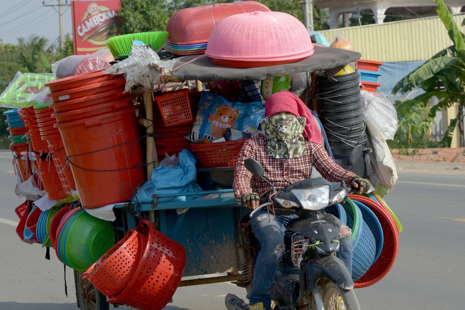 Homem monta sua motocicleta carregada com mercadorias ao longo de uma rua nos arredores de Phnom Penh, no Camboja - 30/10/2017