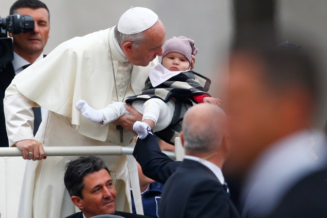 Papa Francisco faz uma pausa para beijar e abençoar um bebê durante sua chegada para liderar a audiência geral de quarta-feira, na Praça São Pedro, no Vaticano - 18/10/2017