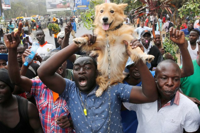 Um apoiador da oposição da coligação Aliança do Quênia Nacional Super Alliance (NASA) segura um cachorro spobre os ombros durante uma manifestação política em Nairobi, no Quênia - 11/10/2017