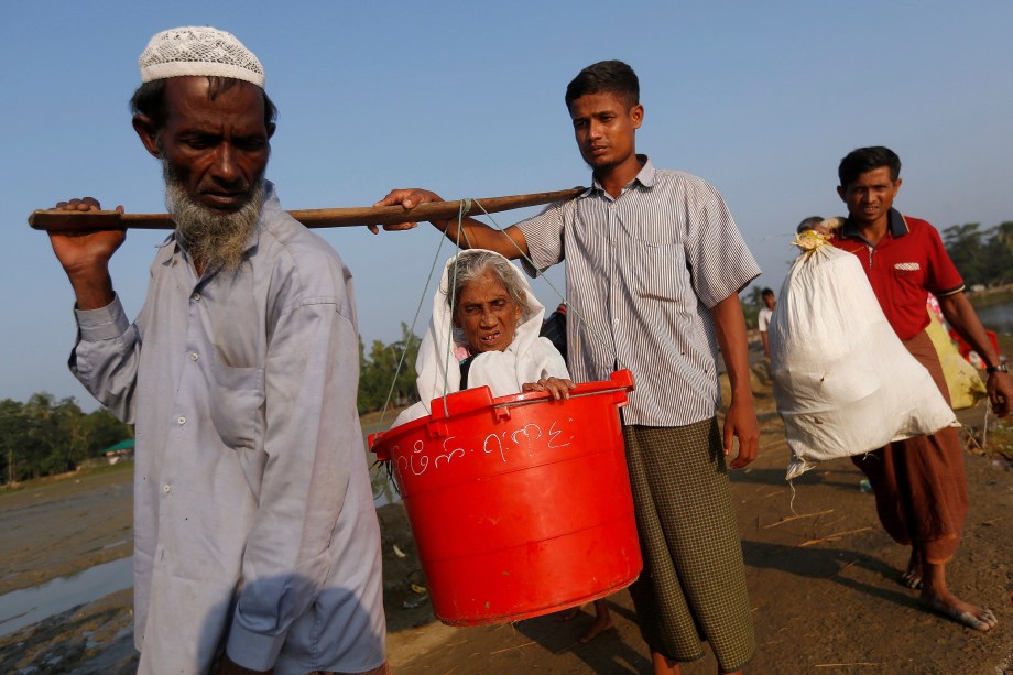 A idosa Boduuzzol Kharun, 97, é carregada por membros da sua família depois de atravessar a fronteira Bangladesh-Mianmar, em Teknaf, Bangladesh - 25/10/2017