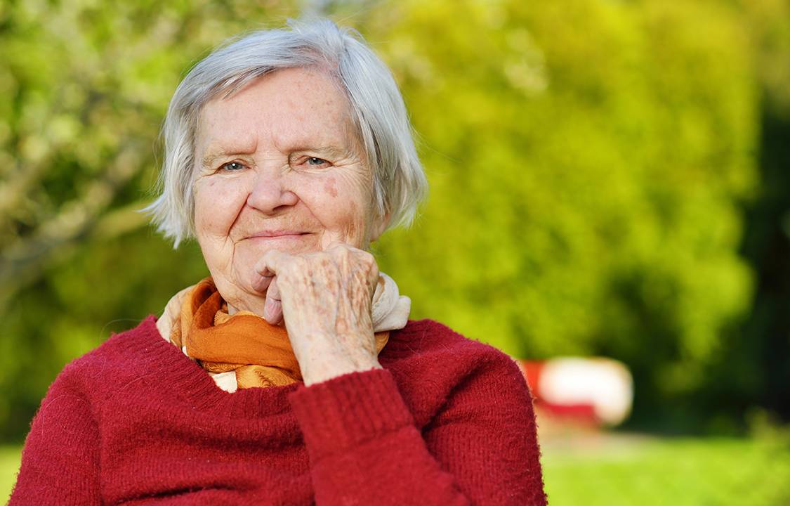 Senhora idosa sorrindo em um jardim