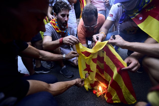 Nacionalistas de direita queimam uma bandeira catalã durante demonstrações contrárias a independência da Catalunha em Valência , na Espanha - 09/10/2017