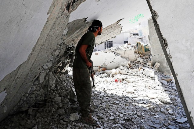 Soldado das Forças Democráticas Sírias se protege em meio a escombros durante combate contra militantes do Estado Islâmico, em Raqqa - 04/10/2017