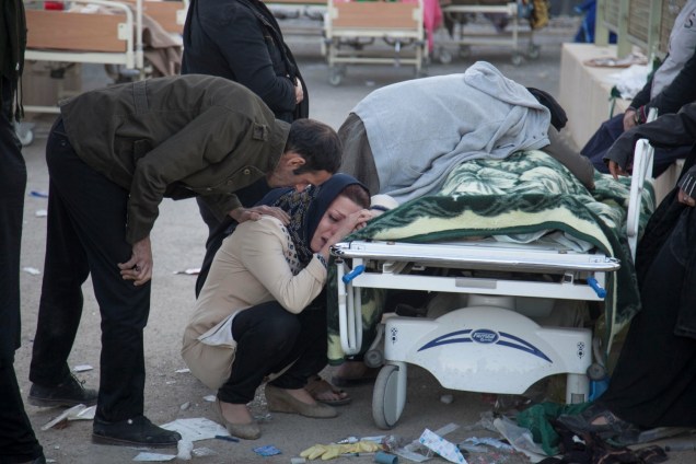 Mulher chora ao lado do corpo de uma vítima após um terremoto no condado de Sarpol-e Zahab, em Kermanshah, no Irã - 13/11/2017