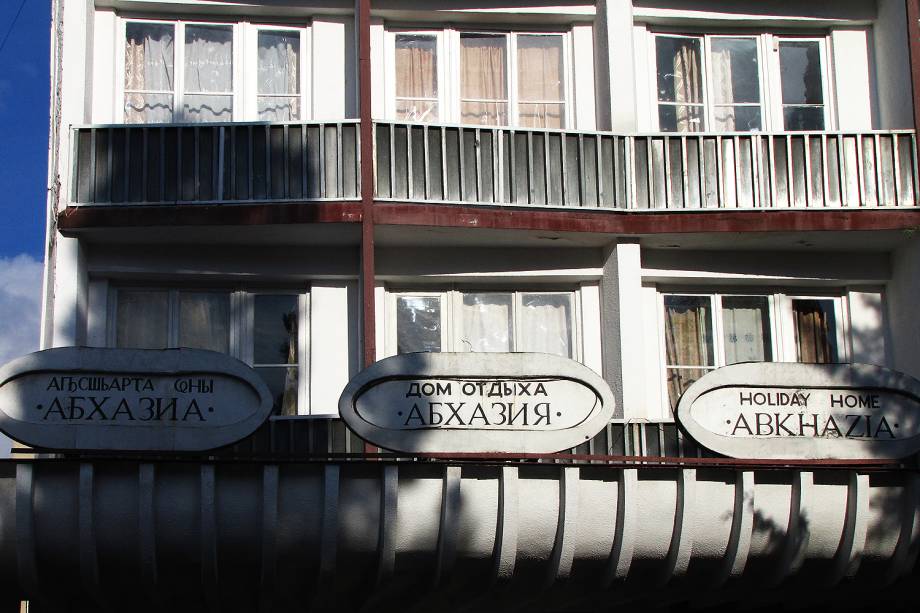 Fachada do hotel Abkhazia com placas em abkhaze, russo e inglês.