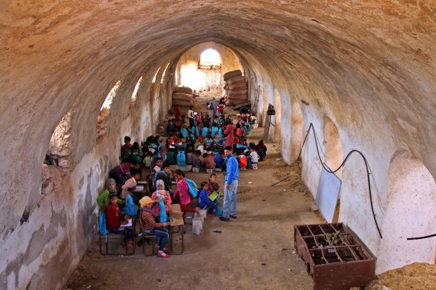 Crianças estudam em um celeiro convertido em sala de aula, na ciade de Daraa, Síria